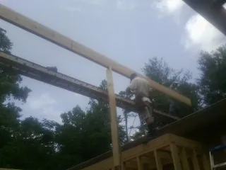 Carpenter setting a ridge beam over a new addition frame — Ice Dam Removal by Roofing Brothers in Jessieville