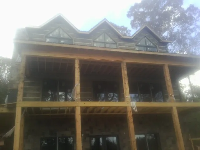 Dormers and porch framing on a large log home under construction — Roof Coating work by our crew in Jessieville