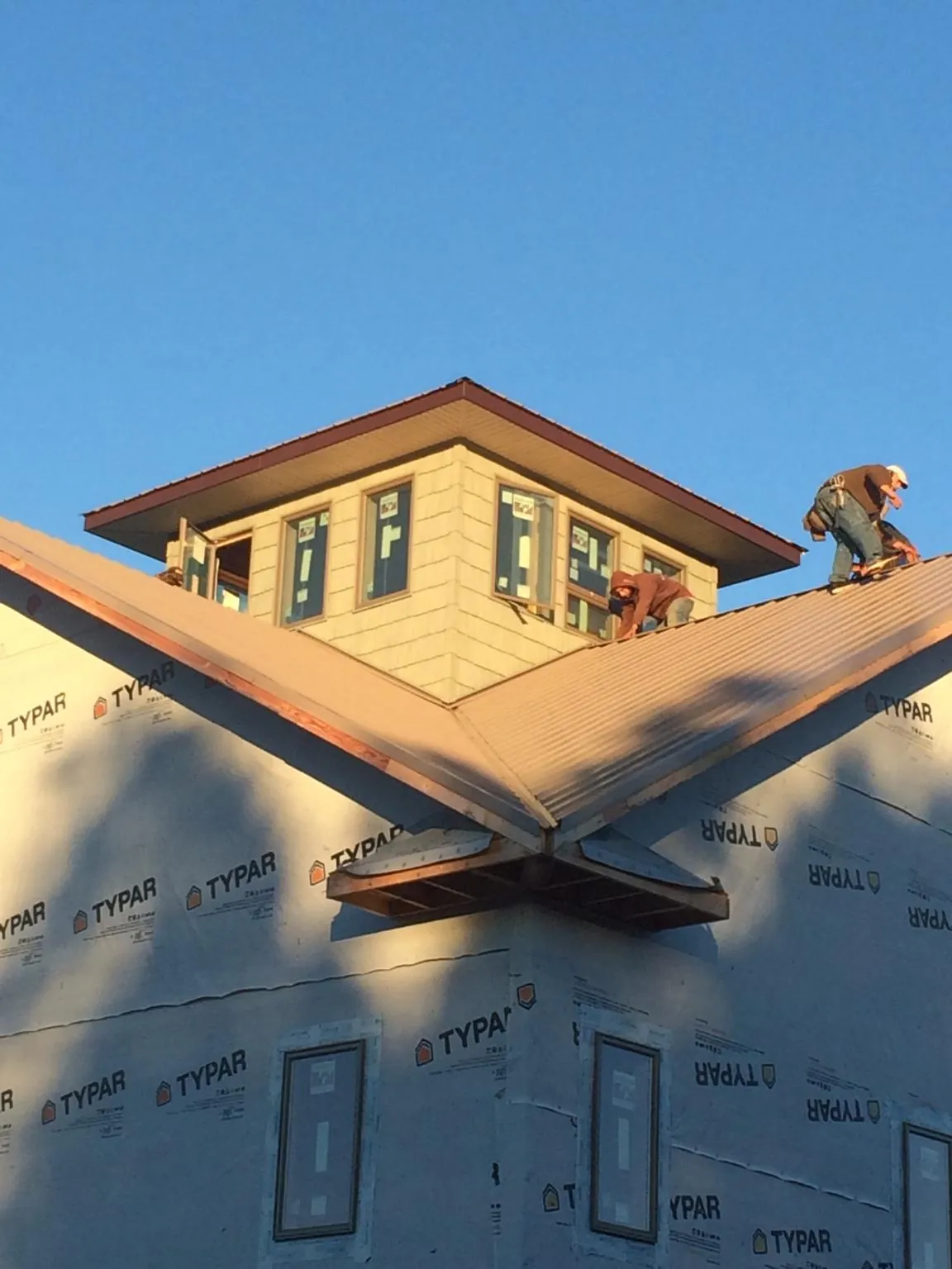 Roofers working around a rooftop cupola on a new metal roof at sunset — Roof Waterproofing in Jessieville by Roofing Brothers